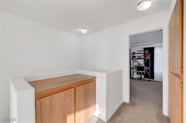 corridor featuring baseboards and light colored carpet