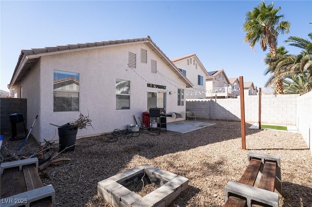 back of property with an outdoor fire pit, a patio area, a fenced backyard, and stucco siding