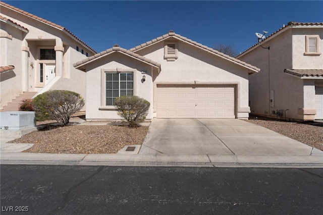 mediterranean / spanish house featuring concrete driveway, an attached garage, a tile roof, and stucco siding