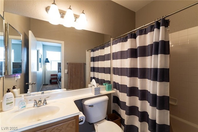 bathroom featuring toilet, shower / bath combo with shower curtain, and vanity