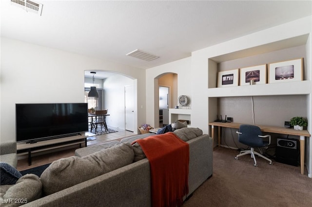 living room featuring visible vents, arched walkways, and carpet flooring