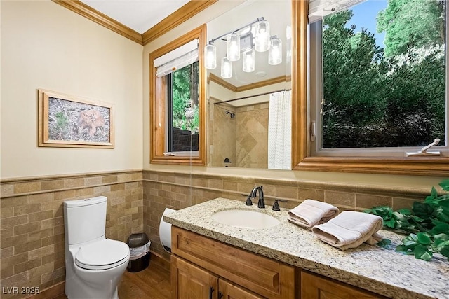 full bath featuring a wainscoted wall, tile walls, toilet, ornamental molding, and vanity