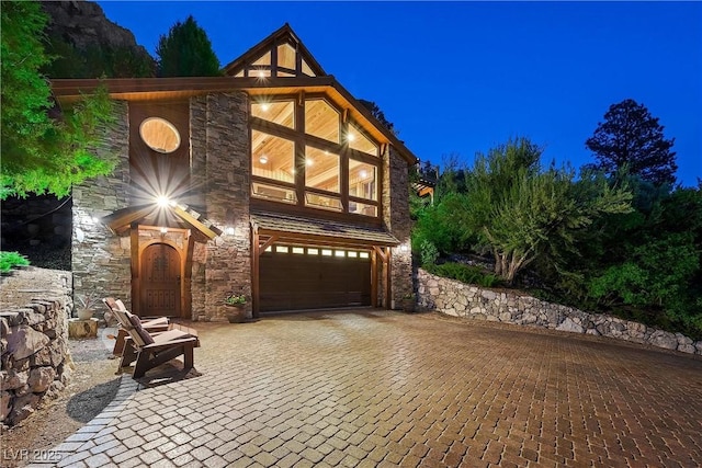 view of front of home with a garage, stone siding, and decorative driveway