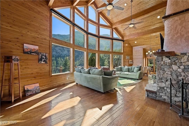 unfurnished living room with a healthy amount of sunlight, wooden walls, wood finished floors, and ceiling fan with notable chandelier