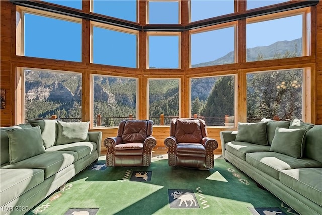 carpeted living area with plenty of natural light, a towering ceiling, and a mountain view