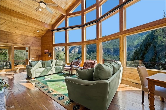 living room with wooden walls, visible vents, wooden ceiling, ceiling fan, and wood finished floors