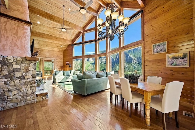 dining space featuring wooden ceiling, wooden walls, wood finished floors, visible vents, and beam ceiling