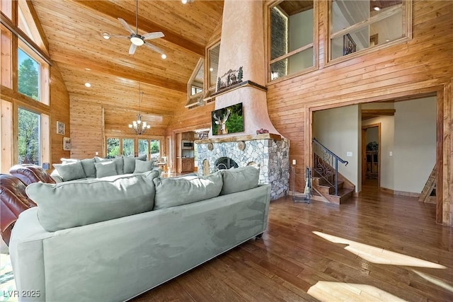 living area with stairs, a stone fireplace, wooden ceiling, and wooden walls