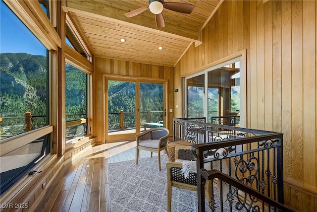 sunroom with ceiling fan, wood ceiling, a mountain view, and vaulted ceiling