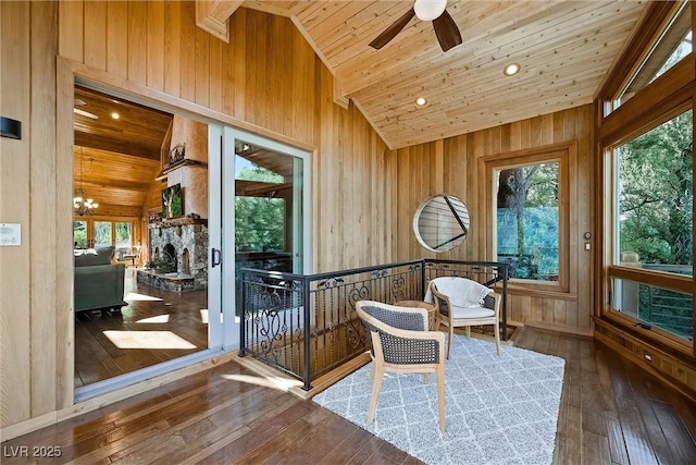 sunroom / solarium featuring wood ceiling, vaulted ceiling, a stone fireplace, and ceiling fan with notable chandelier