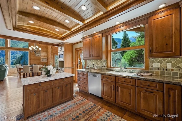 kitchen with beam ceiling, stainless steel appliances, brown cabinetry, a sink, and wood finished floors