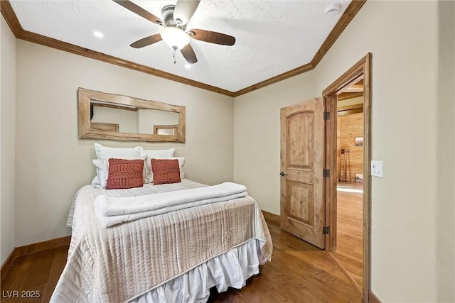 bedroom with a ceiling fan, crown molding, baseboards, and wood finished floors