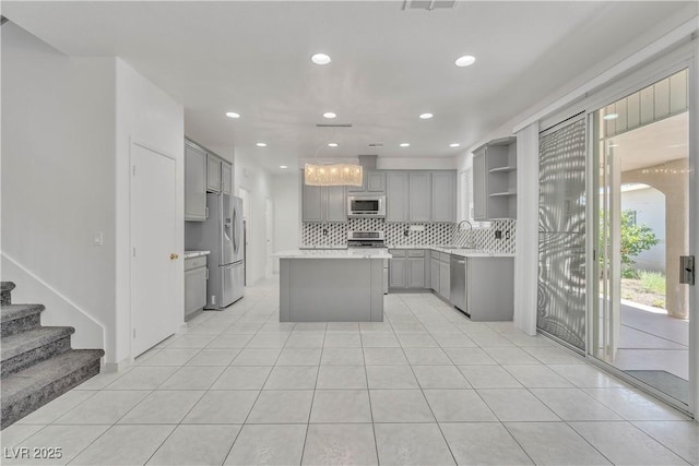 kitchen with open shelves, stainless steel appliances, gray cabinets, light countertops, and a kitchen island