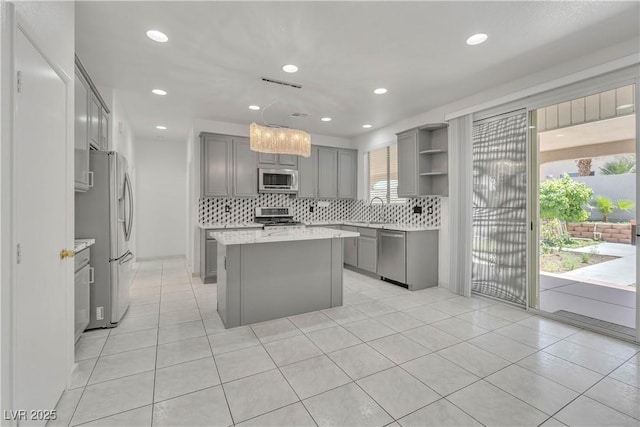 kitchen with gray cabinetry, hanging light fixtures, appliances with stainless steel finishes, a center island, and open shelves