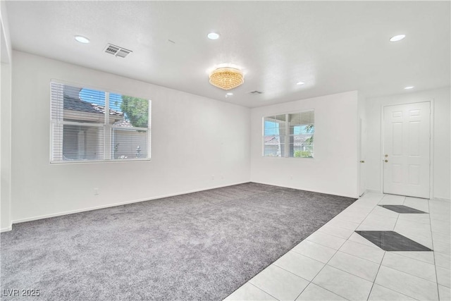 empty room with light tile patterned floors, recessed lighting, visible vents, and light colored carpet