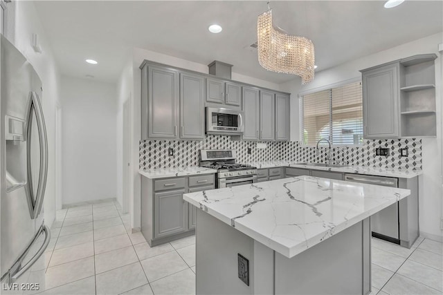 kitchen with hanging light fixtures, appliances with stainless steel finishes, open shelves, and a center island