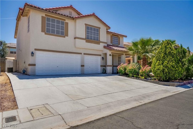 mediterranean / spanish home with a garage, concrete driveway, a tile roof, and stucco siding