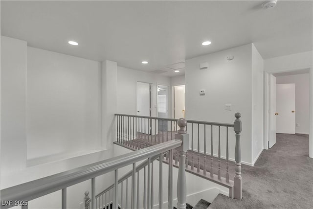 hallway with carpet floors, recessed lighting, baseboards, and an upstairs landing