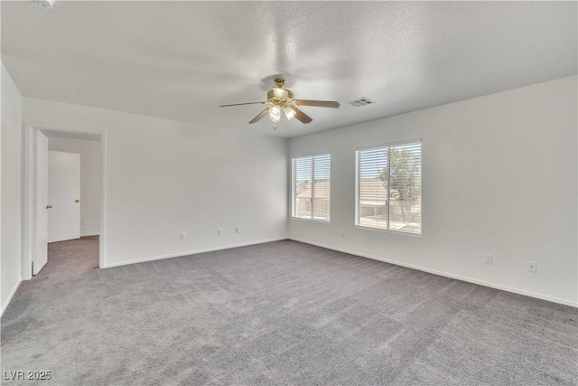 carpeted empty room featuring baseboards, ceiling fan, visible vents, and a textured ceiling