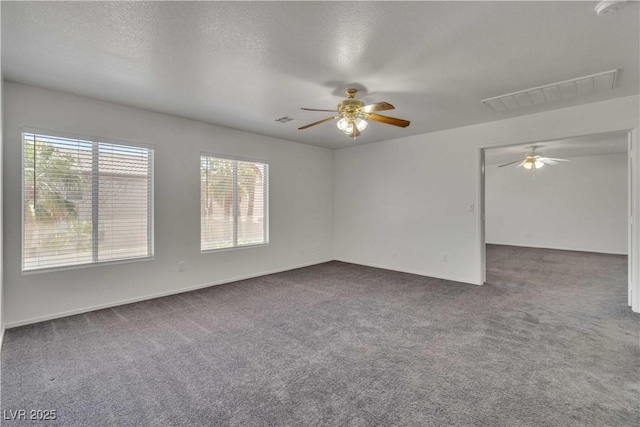 unfurnished room with a ceiling fan, visible vents, dark carpet, and a textured ceiling