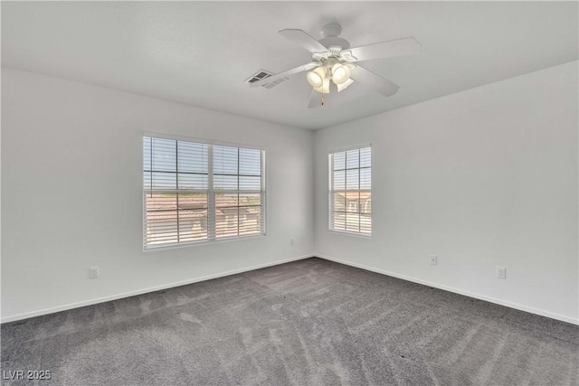 empty room with a ceiling fan, visible vents, dark carpet, and baseboards