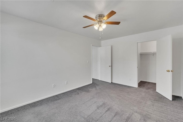 unfurnished bedroom with ceiling fan, baseboards, a spacious closet, a closet, and dark colored carpet