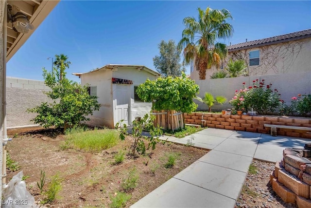 view of yard featuring a fenced backyard, an outdoor structure, and a patio