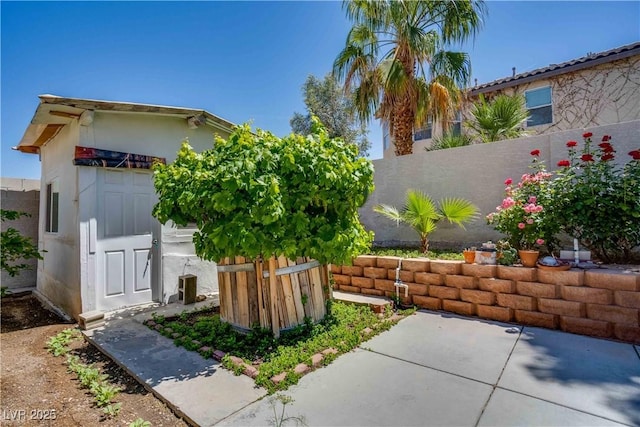 view of side of home featuring an outbuilding, fence, and stucco siding