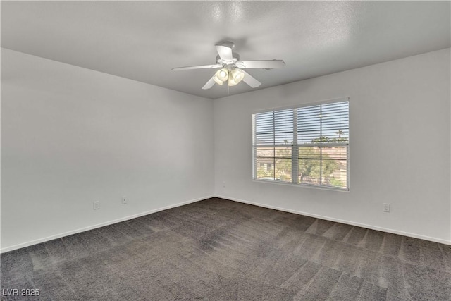 spare room featuring a ceiling fan, dark colored carpet, and baseboards