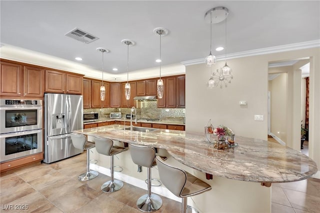 kitchen with stainless steel appliances, a breakfast bar, visible vents, and decorative light fixtures