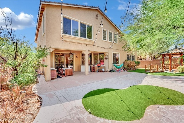 rear view of property with a patio, fence, a gazebo, and stucco siding