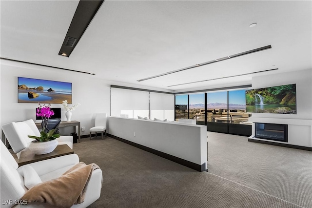 living area with baseboards, a fireplace, and dark carpet