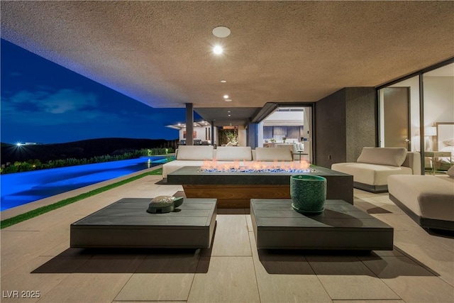 patio at twilight featuring an outdoor living space with a fire pit