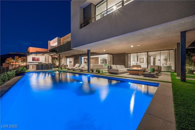 pool at twilight with an outdoor hangout area, a patio area, and a fenced in pool