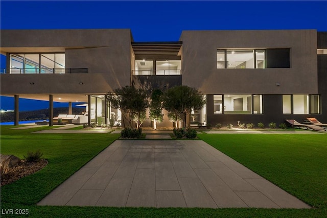 exterior space with a lawn, a balcony, and stucco siding