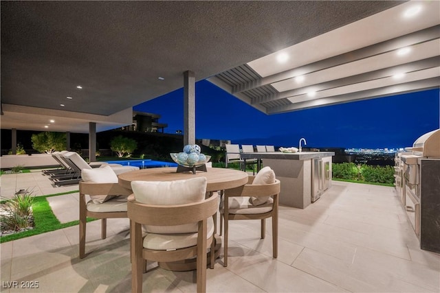 patio at night with outdoor dining area, a pool, area for grilling, a sink, and exterior bar