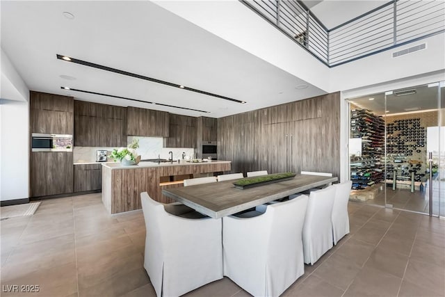 kitchen featuring light tile patterned floors, a kitchen island with sink, visible vents, and modern cabinets