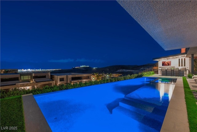 pool at twilight with a patio and a pool with connected hot tub