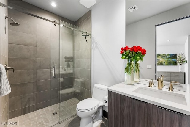 bathroom featuring toilet, a stall shower, vanity, and visible vents