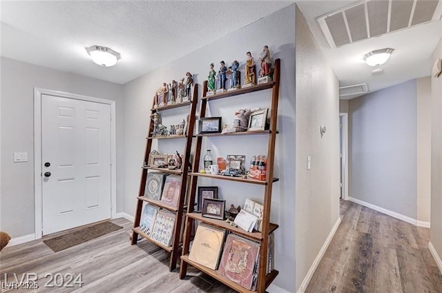 foyer with baseboards, a textured ceiling, visible vents, and wood finished floors