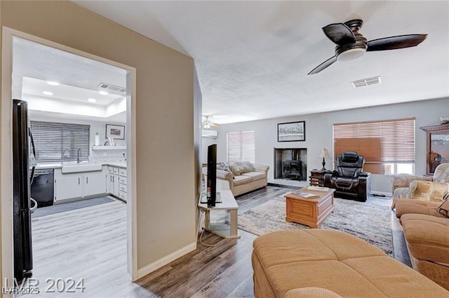 478 Potomac St, Henderson, NV 89015 - living room featuring a fireplace with raised hearth, light wood-style flooring, visible vents, and a ceiling fan