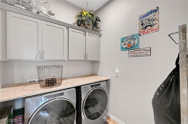 laundry room with washing machine and dryer, cabinet space, and baseboards