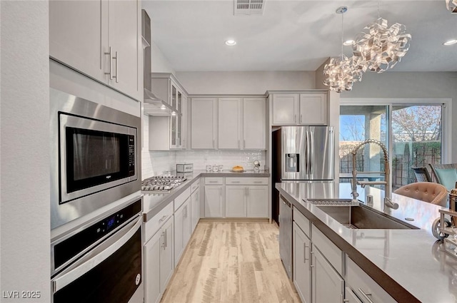 kitchen with light wood finished floors, visible vents, appliances with stainless steel finishes, a sink, and backsplash