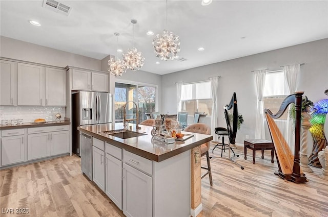 kitchen featuring light wood-type flooring, dark countertops, visible vents, and a sink