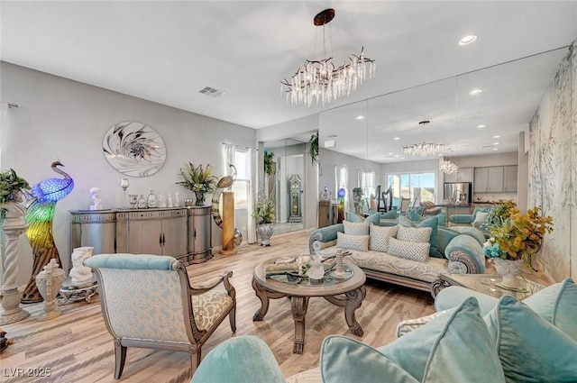 living area featuring light wood finished floors, visible vents, a notable chandelier, and recessed lighting