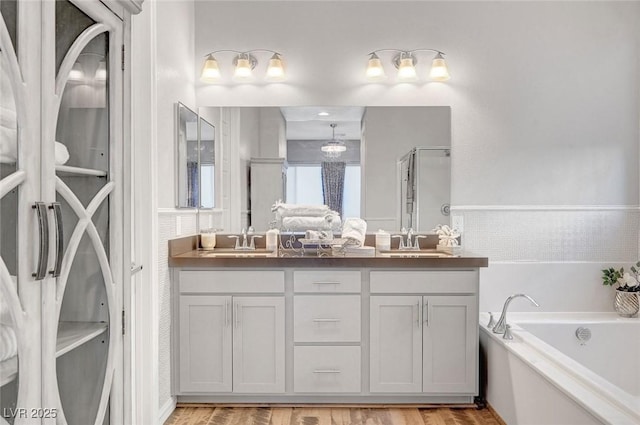 bathroom featuring a shower with shower door, a sink, a bath, and double vanity