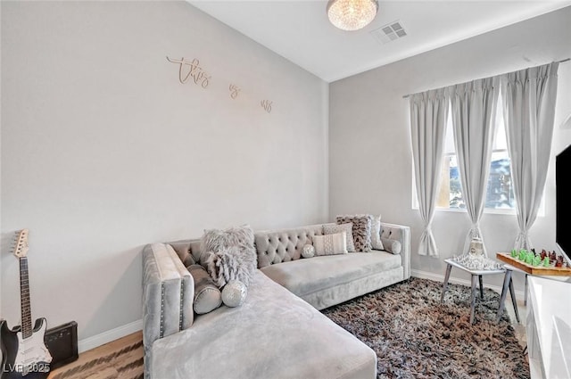 living area with wood finished floors, visible vents, and baseboards