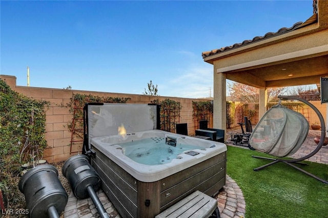 view of patio with a hot tub and fence