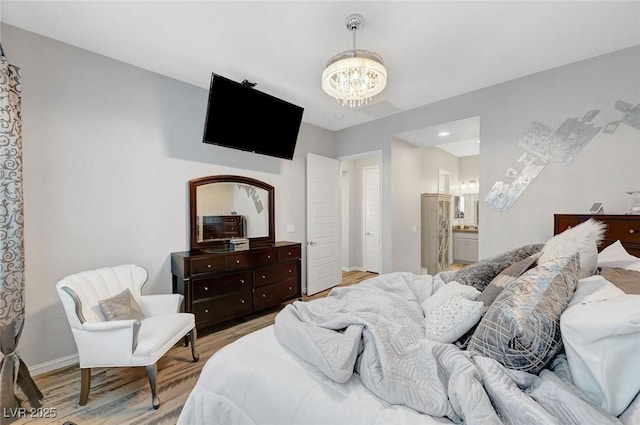 bedroom with a notable chandelier, ensuite bath, baseboards, and wood finished floors