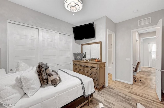 bedroom with a closet, light wood-type flooring, visible vents, and baseboards